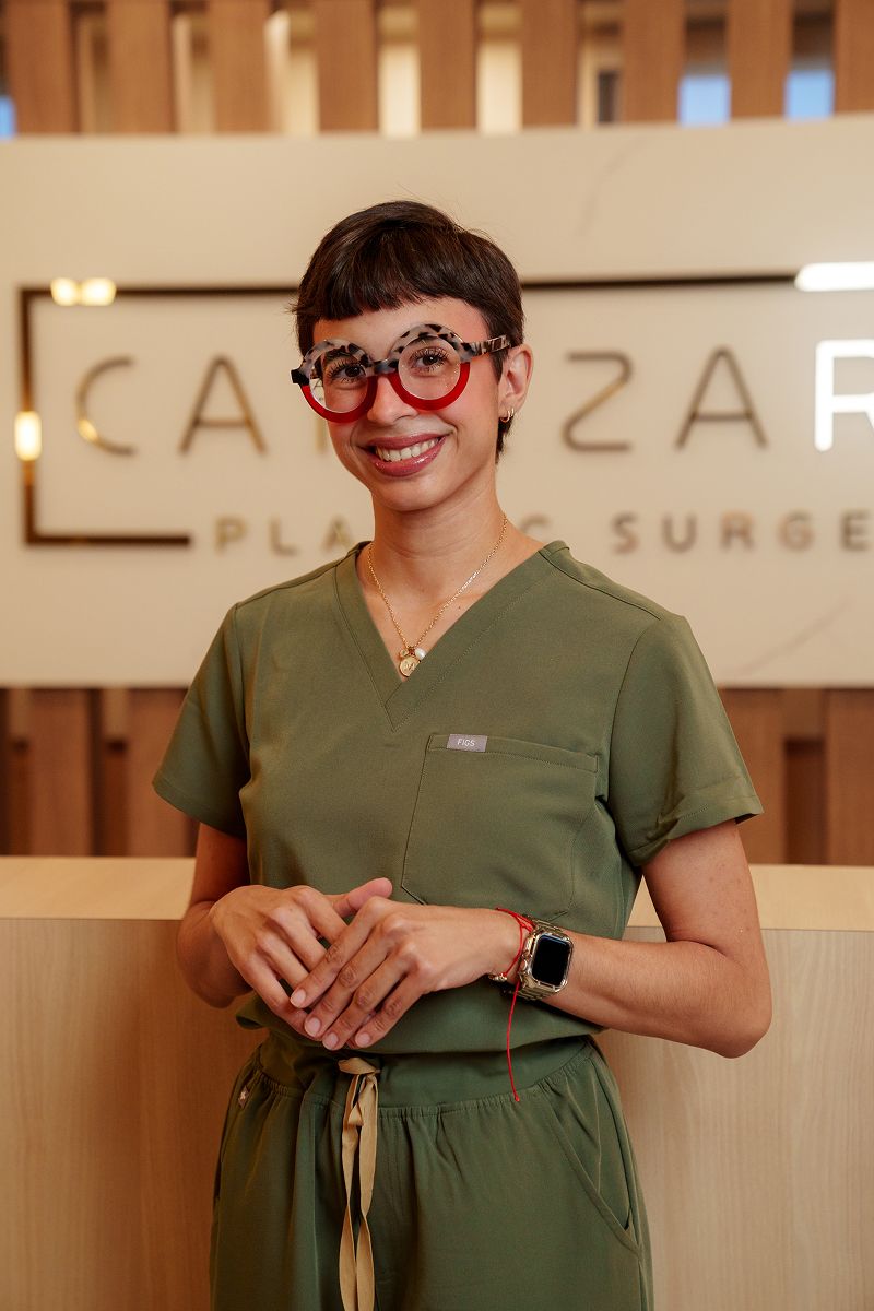 Smiling professional in medical attire with glasses.