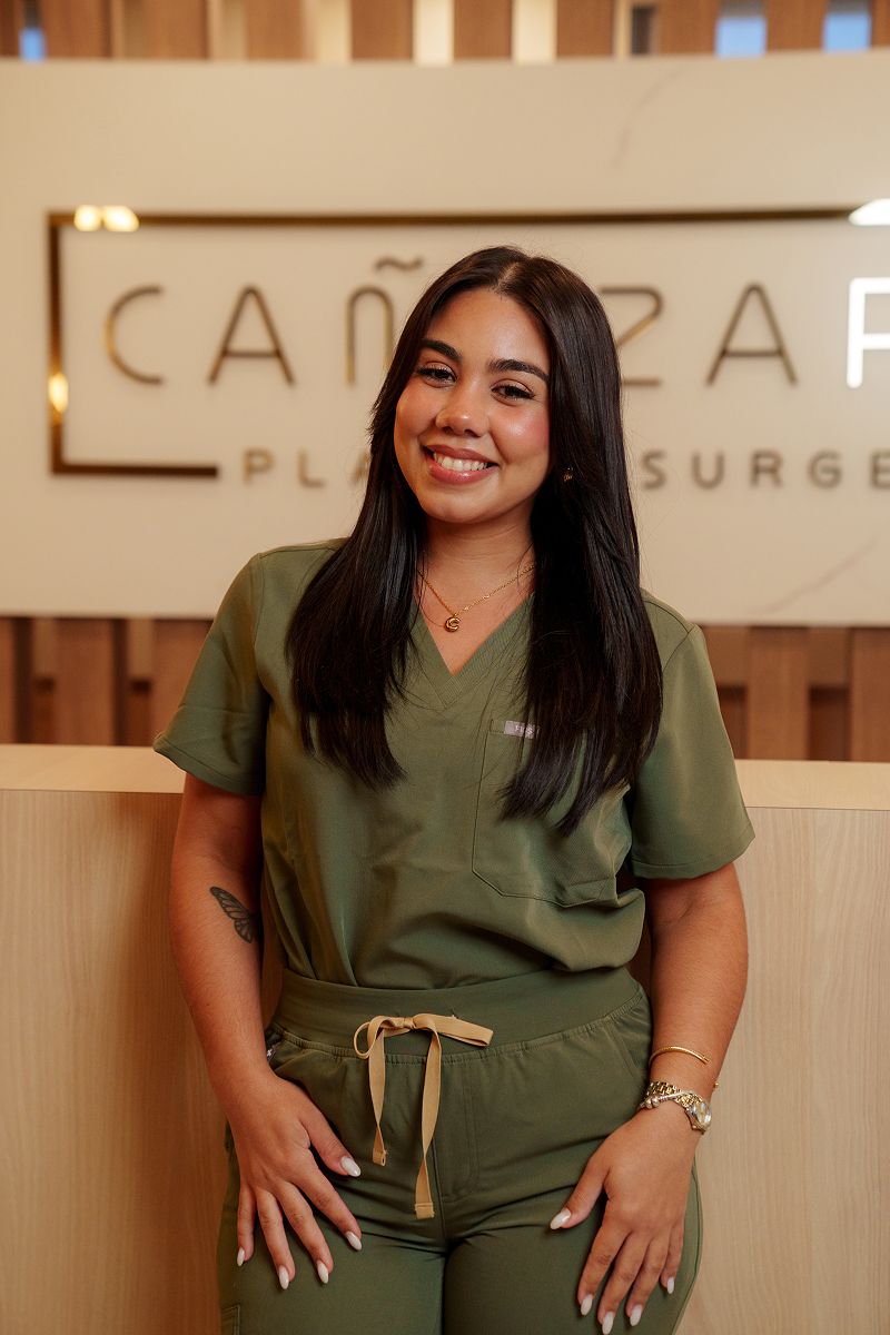 Smiling woman in green scrubs at clinic.