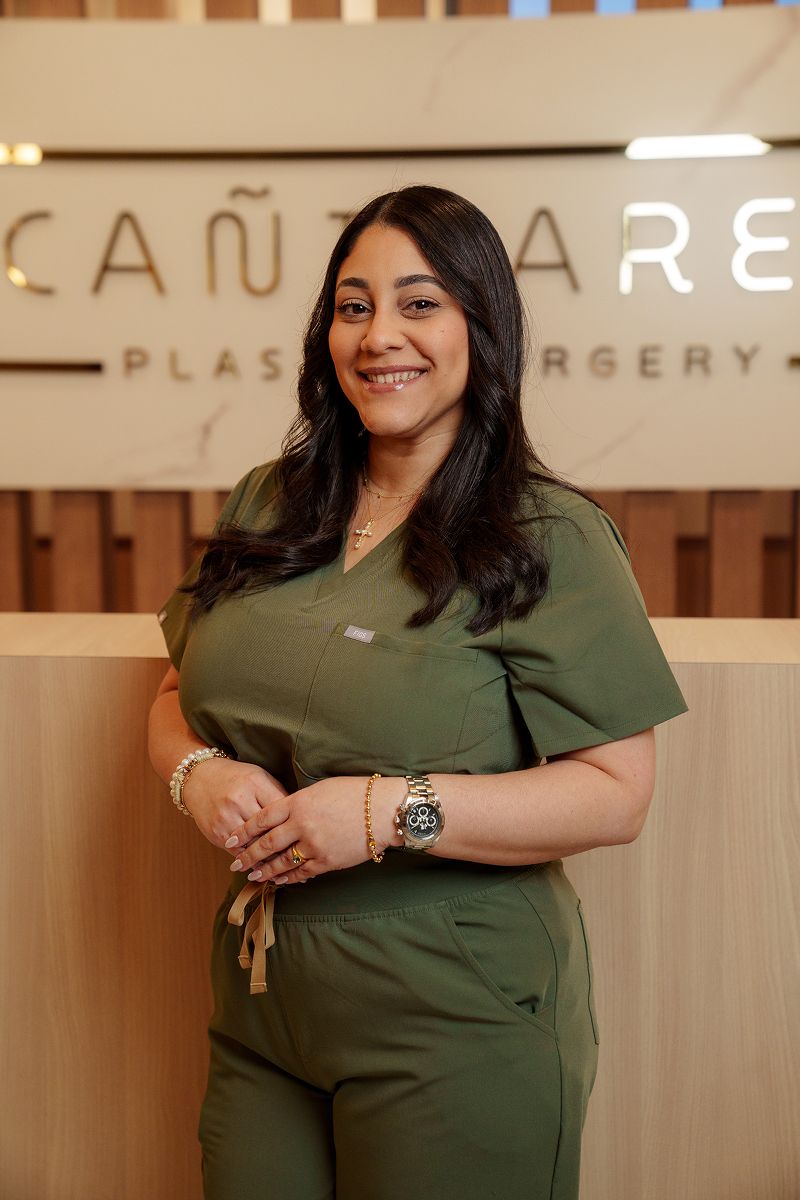 Smiling woman in medical scrubs at clinic.