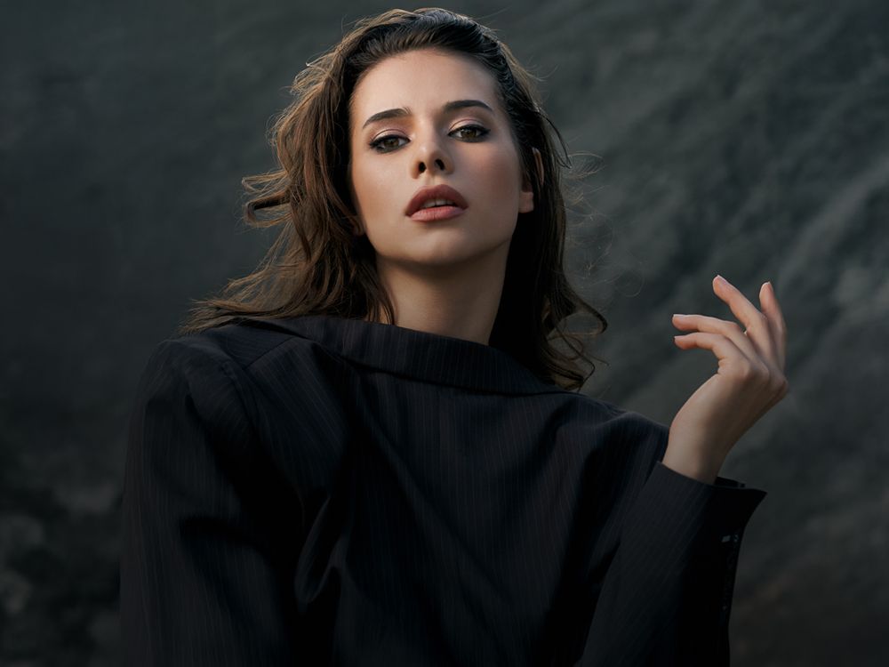 Woman posing elegantly in stylish black attire.