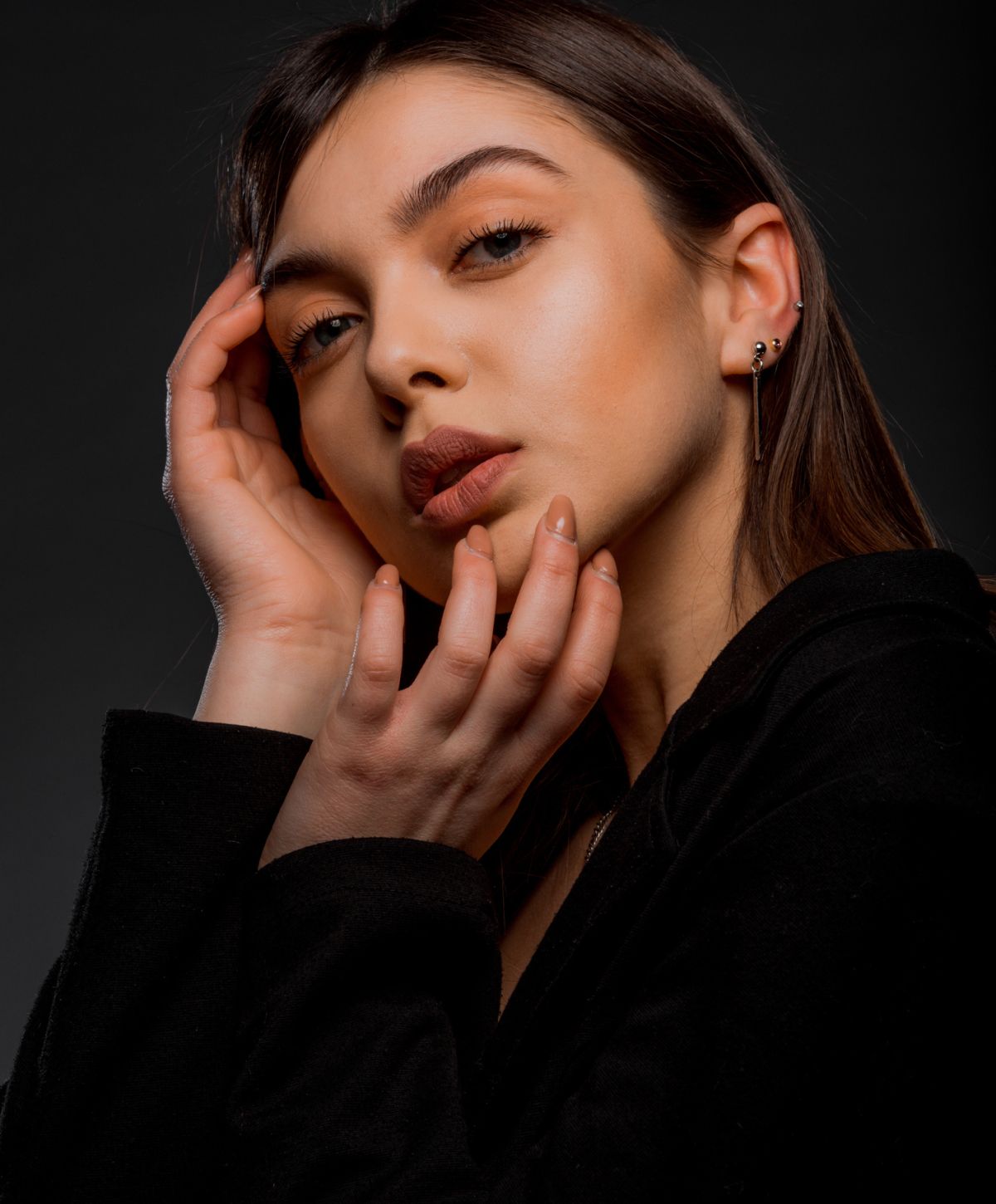 Woman with hands on face, dramatic lighting.