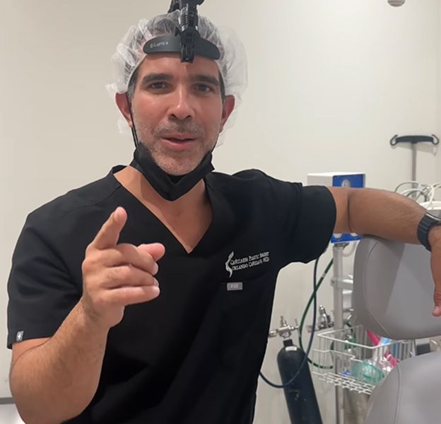 Doctor in scrubs pointing in dental clinic.