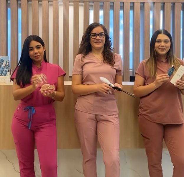 Three women in scrubs standing in clinic.