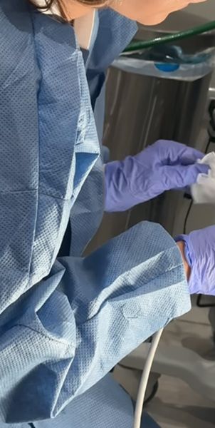 Medical professional in surgical attire preparing equipment.