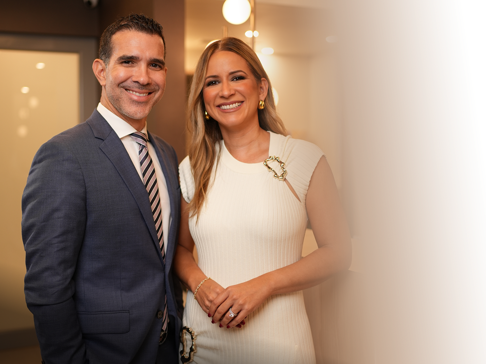 Two smiling individuals in elegant attire.