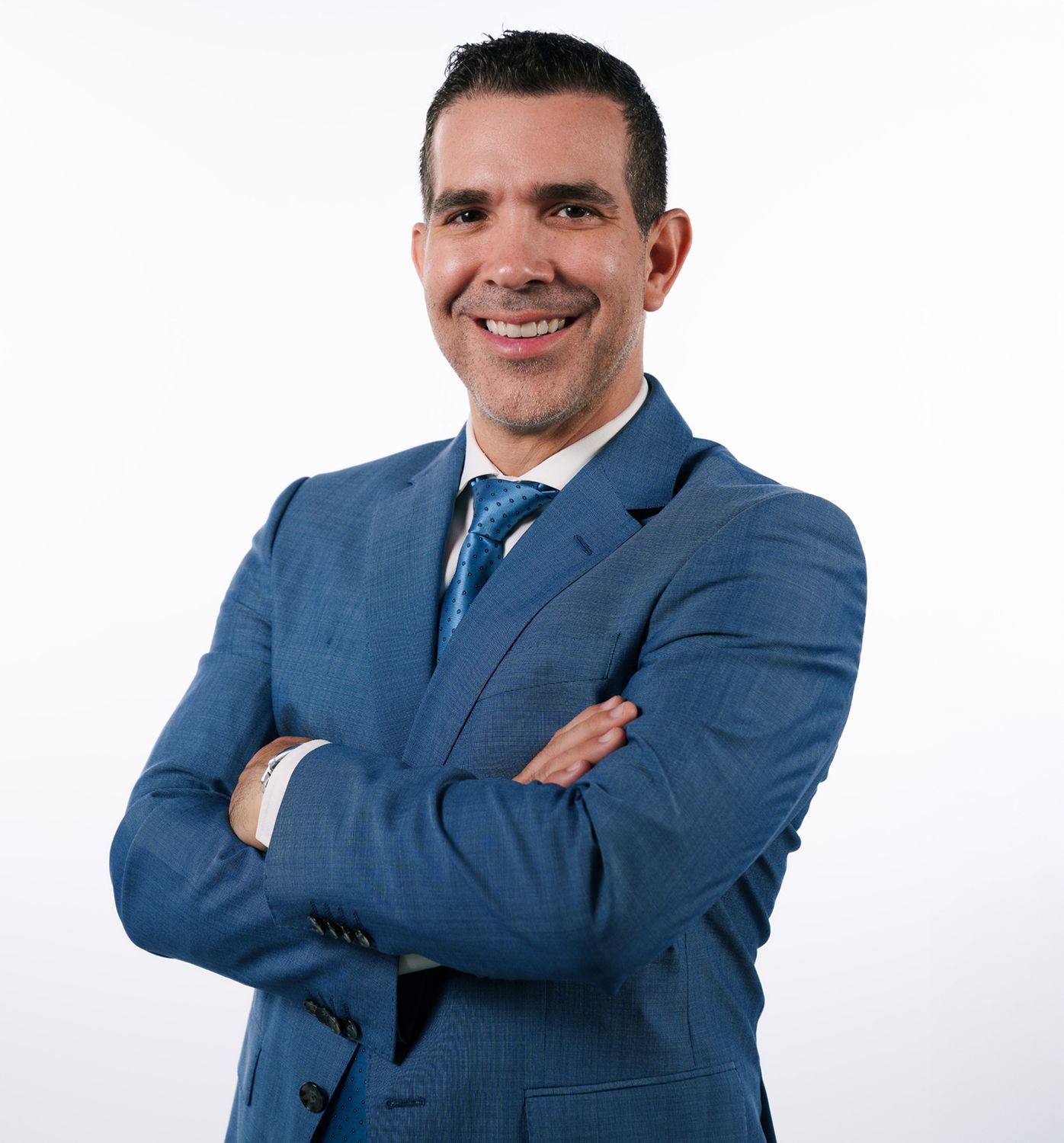 Smiling man in a blue suit with crossed arms.